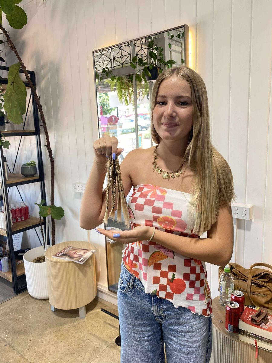 A client holding the plaited ponytail she donated at Winter & Co.